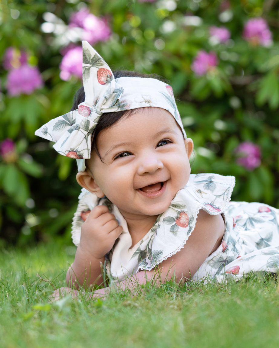 barnfotografering utomhus i trädgård med blommor, baby som skrattar